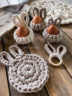 crocheted egg holders with two eggs in them on a wooden table next to a rug