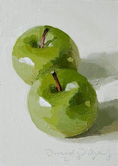 two green apples sitting side by side on a white surface