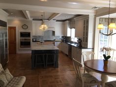 a kitchen and dining room with an island in the middle, wood flooring and white cabinets