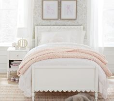 a white bed sitting in a bedroom next to two framed pictures on the wall above it