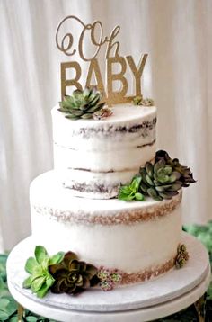 a three tiered cake with succulents on top and the word baby spelled in gold