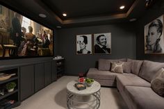 a living room with grey walls and pictures on the wall above the couches, along with a white coffee table