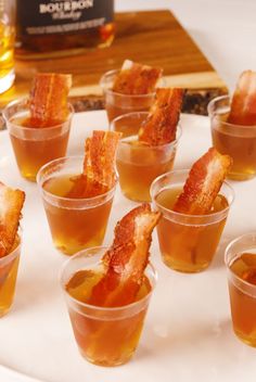 small cups filled with different types of food on a white plate next to a bottle