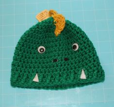 a green crocheted hat with eyes and nose