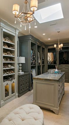 a walk in closet with an island and chandelier