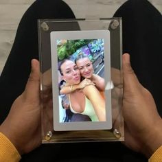 a person holding up a photo frame with two people in it and the image is being taken