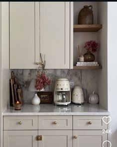 a kitchen with white cupboards and marble counter tops in the center, surrounded by wooden shelves