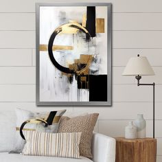 a living room with white couches and black and gold artwork hanging on the wall