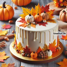 a white cake decorated with fall leaves and pumpkins on a wooden table surrounded by other autumn decorations