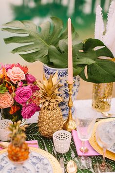 the table is set with pineapples, flowers and other decorative items on it