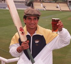 a man holding a baseball bat and a glass of beer in front of an empty stadium