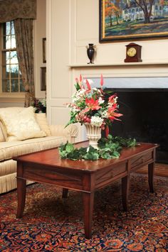 a living room with a couch, coffee table and painting on the fireplace mantel