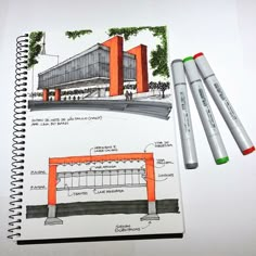 a notebook with two markers and an architectural drawing on the cover next to some pens