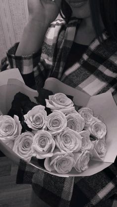 a woman holding a bouquet of roses on her cell phone and looking at the camera