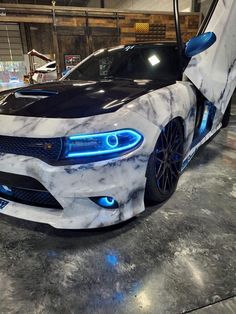 a white and black car with blue lights on it's front bumper is parked in a garage