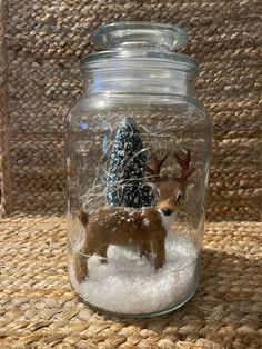 a glass jar filled with snow and a deer figurine