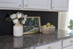 a bowl of fruit sitting on top of a counter next to a vase with flowers