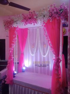 a bed with pink curtains and flowers on the headboard is decorated in white and pink