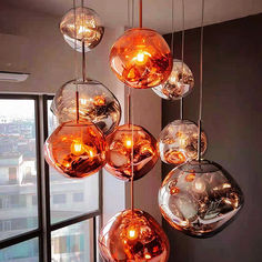 a bunch of glass balls hanging from a ceiling in front of a window with city view