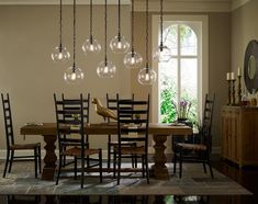 a dining room table and chairs with lights hanging from the ceiling