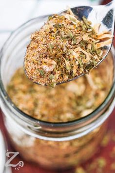 a spoon with some food in it on top of a glass jar filled with something