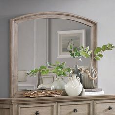 a mirror sitting on top of a dresser next to a plant