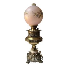 an old fashioned lamp with a pink glass ball on top and gold trimmings