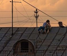 two men sitting on the roof of an old building