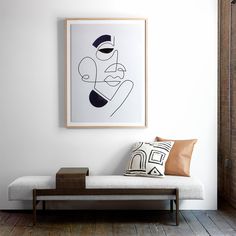 a white couch sitting next to a wooden floor under a framed art on the wall