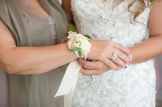 two brides holding hands with wedding rings on their fingers and flowers in the other hand