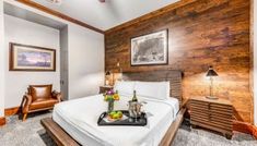 a bedroom with wood paneling and white bedding