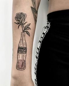 a woman's arm with a rose in a bottle tattoo on the left forearm