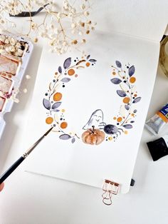 someone is painting an autumn wreath with watercolors