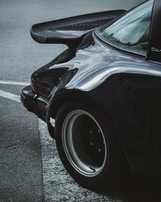 the back end of a black sports car parked in a parking lot next to a curb