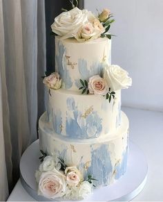 a three tiered wedding cake with white and blue flowers