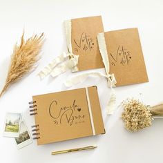 two brown notebooks sitting on top of a table next to dried flowers and other items