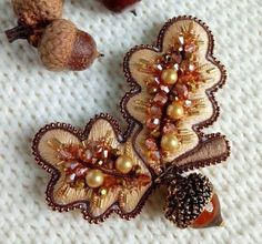 two brooches with beads and acorns are laying on a knitted surface