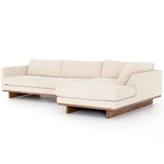 a white sectional couch with wooden legs