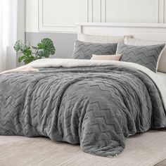 a bed with grey comforter and pillows