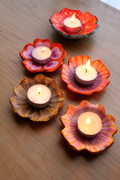 four candles are sitting in flower shaped bowls