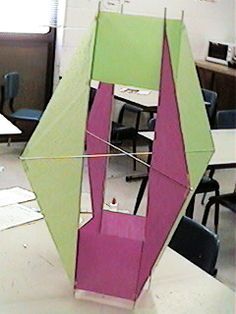 a kite that is in the middle of a room with desks and chairs behind it