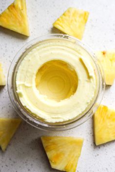 some pieces of pineapple sitting on top of a white table with cream cheese in the middle