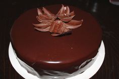 a chocolate cake sitting on top of a white plate covered in frosted icing