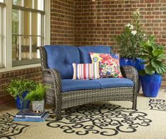 a blue couch sitting on top of a rug next to a potted plant in front of a window