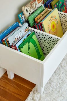 a white wooden box filled with books on top of a floor