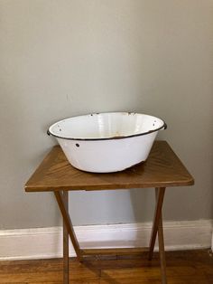 a large white bowl sitting on top of a wooden table next to a gray wall