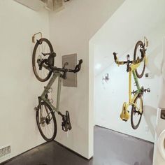 there is a bike mounted to the wall in this bathroom with two bicycles on it