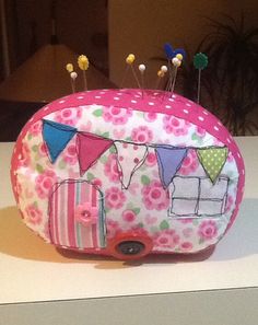 a pink and white purse with some pins in the middle of it on a table