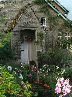 an old brick house with flowers around it