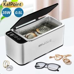 an image of a silver lunch box with glasses and jewelry on the table next to it